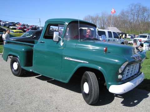 1991 Ford LTD Crown Victoria - A green 1955 Chevrolet 3100 pickup truck is seen at an outdoor car show with other vehicles in the background.