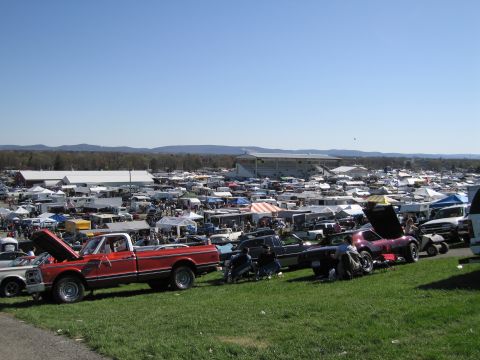 1991 Ford LTD Crown Victoria - A wide view of a car show with numerous vehicles and vendors under a clear blue sky.