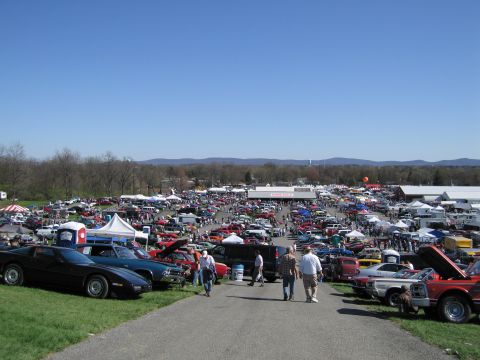 1991 Ford LTD Crown Victoria - A large gathering of vehicles and vendors at an outdoor car show event.