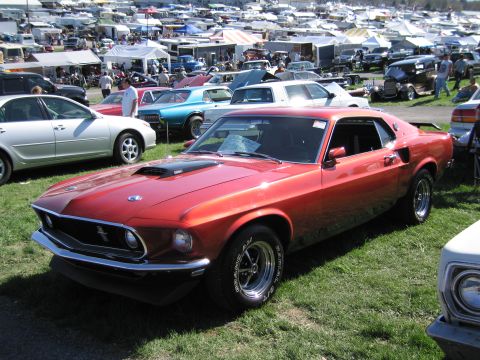 1991 Ford LTD Crown Victoria - A classic red Ford Mustang Mach 1 is displayed at an outdoor automotive event.