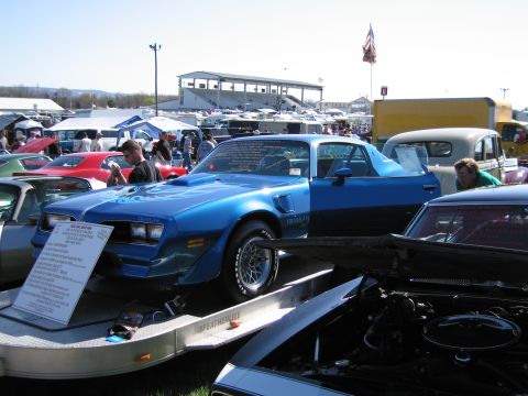 1991 Ford LTD Crown Victoria - A blue 1979 Pontiac Firebird Trans Am is displayed on a trailer at an outdoor car show with other vehicles present.