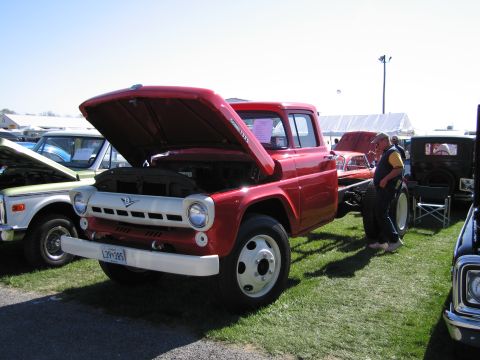 1991 Ford LTD Crown Victoria - A red truck with its hood open is displayed at an outdoor event, with other vehicles visible in the background.