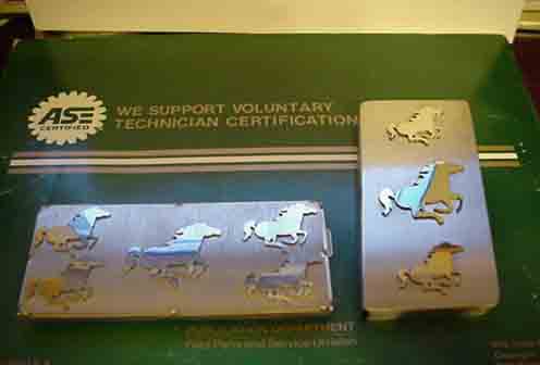 Two metal plates with running horse emblems, one rectangular and one square, on top of a green document
