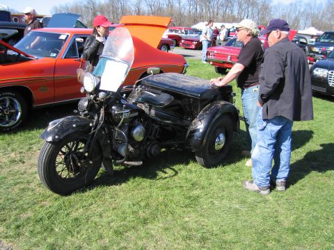 1991 Ford LTD Crown Victoria - A black three-wheeled motorcycle with a sidecar is displayed outdoors on a grassy field.