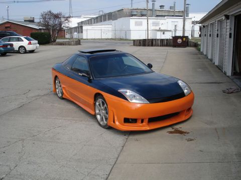 1995 Ford Probe - A modified sports coupe with a two-tone paint scheme and aggressive body kit is shown from a three-quarter front angle.