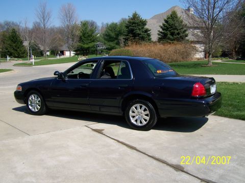 2003 Ford Crown Victoria - Side view of a 2003 Ford Crown Victoria parked on a suburban driveway.