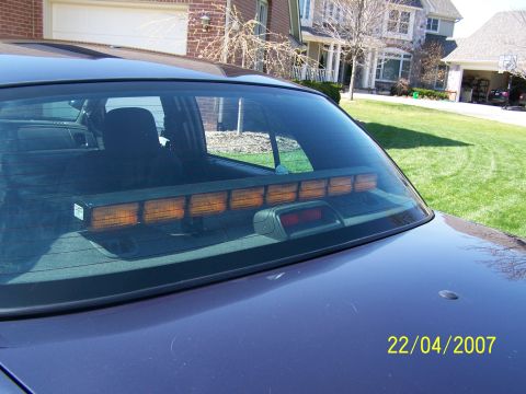 2003 Ford Crown Victoria - Rear view of a car showing an amber light bar mounted inside the back window.