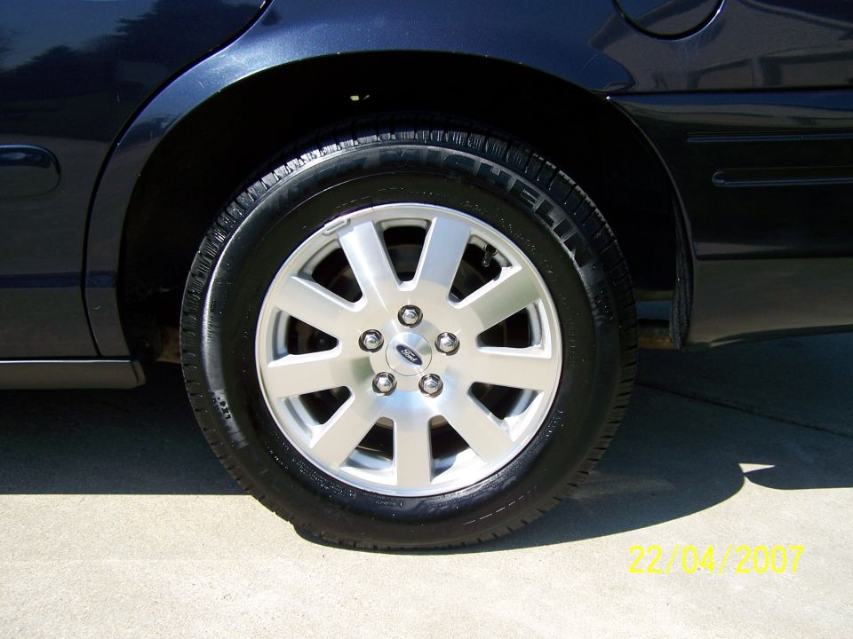 Dark blue car's rear wheel with silver 5-spoke Ford alloy rim
