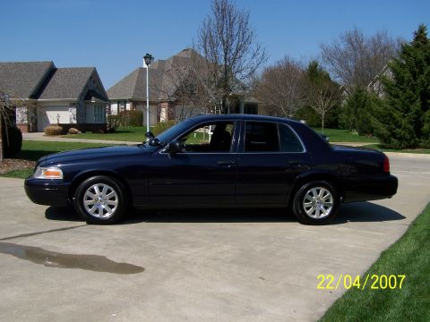 2003 Ford Crown Victoria - Side view of a dark blue 2003 Ford Crown Victoria parked on a suburban driveway.
