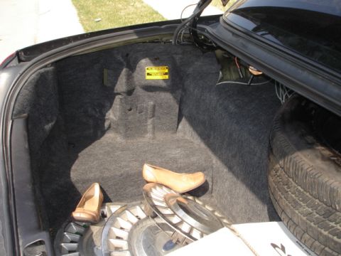 2001 Ford Crown Victoria - The trunk of a car contains a spare tire, hubcaps, and a pair of tan shoes.