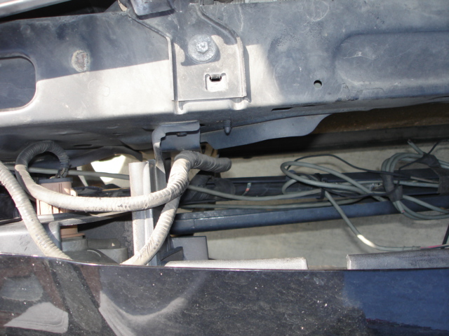 Underside of a vehicle's front end, showing wiring harnesses and frame components