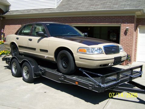2003 Ford Crown Victoria - A tan and brown 2003 Ford Crown Victoria is seen being transported on a trailer.