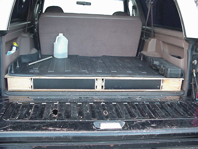 Rear cargo area of Ford Bronco with plywood storage drawer platform and water jug
