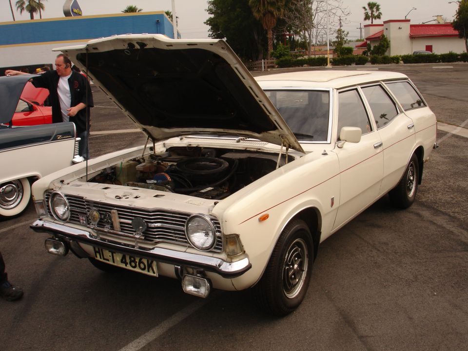 White station wagon, hood open, showing engine. License plate HLT 486K. Side view
