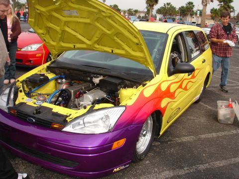 1993 Ford Taurus - Customized yellow station wagon with flames and engine exposed at an outdoor event.
