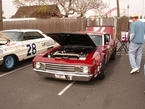 1993 Ford Taurus - Two race cars parked side-by-side, one red and one white, with hoods open.