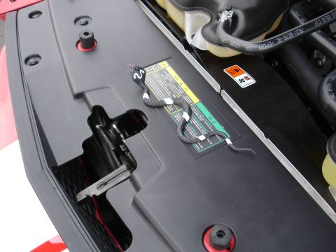 1993 Ford Taurus - A toy snake rests on the engine cover of a vehicle, near some warning labels.