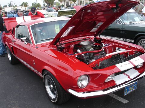1993 Ford Taurus - A bright red 1967 Shelby GT500 is displayed with its hood open, revealing the engine. The car has white racing stripes and a California lic…