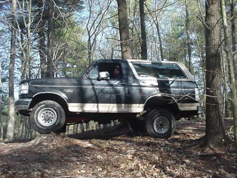1993 Ford Bronco - This 1993 Ford Bronco navigates a wooded trail, with one wheel elevated on a tree stump.