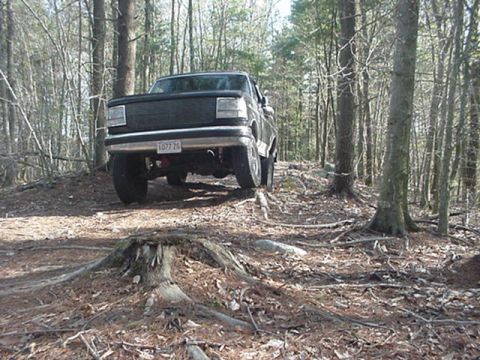 1993 Ford Bronco - Rear view of a 1993 Ford Bronco driving on a dirt path in a forest.