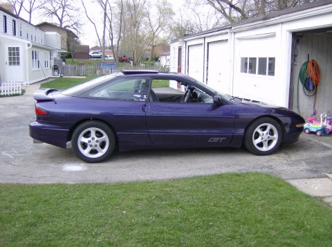 1996 Ford Probe - A purple 1996 Ford Probe GT coupe is parked in a driveway next to a garage.