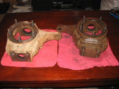 1991 Ford Bronco - Two rusty Dana 60 front axle knuckles are shown resting on red cloths on a wooden surface.