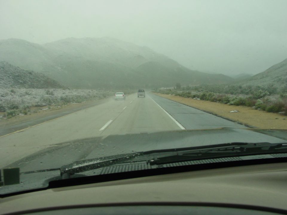 driving on a highway with mountains in the background and two cars ahead