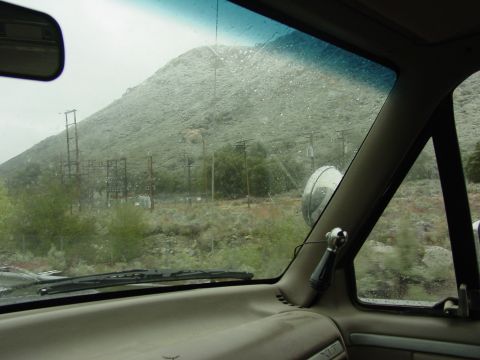 1994 Ford Bronco - The view from inside a vehicle shows a mountain landscape with power lines and trees under a rainy sky.