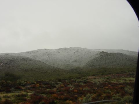 1994 Ford Bronco - A view of hills covered in snow and green vegetation under a cloudy sky.