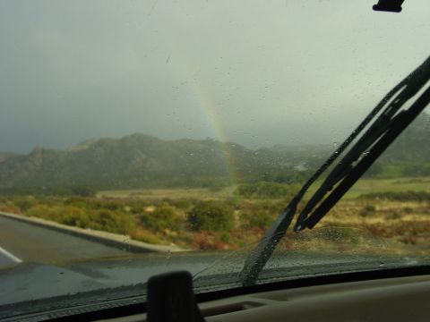 1994 Ford Bronco - A rainbow appears through the rain as seen from inside a vehicle.