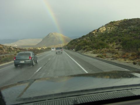 1994 Ford Bronco - A rainbow arcs over a mountain as several vehicles travel down a wet highway.