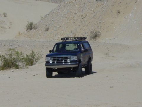 1994 Ford Bronco - This 1994 Ford Bronco is captured in a desert landscape, equipped with a roof rack for off-road adventures.