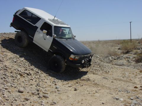 1994 Ford Bronco - This Ford Bronco is navigating a challenging off-road terrain with steep inclines and loose rocks.