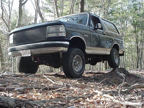 1993 Ford Bronco - This Ford Bronco is navigating rough terrain in a forest setting.