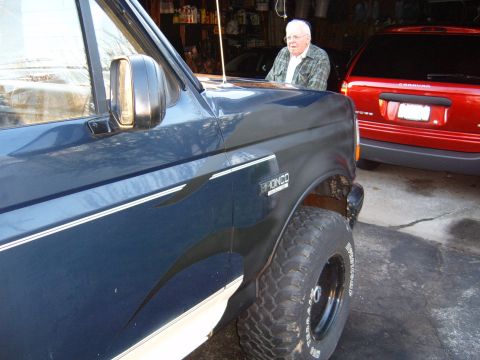 1993 Ford Bronco - A blue SUV with a 'BRONCO' badge is parked next to a red minivan.
