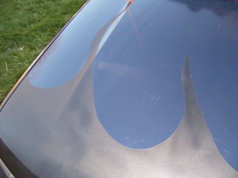 1993 Ford Bronco - Close-up of a car hood with custom flame paintwork and signs of wear.