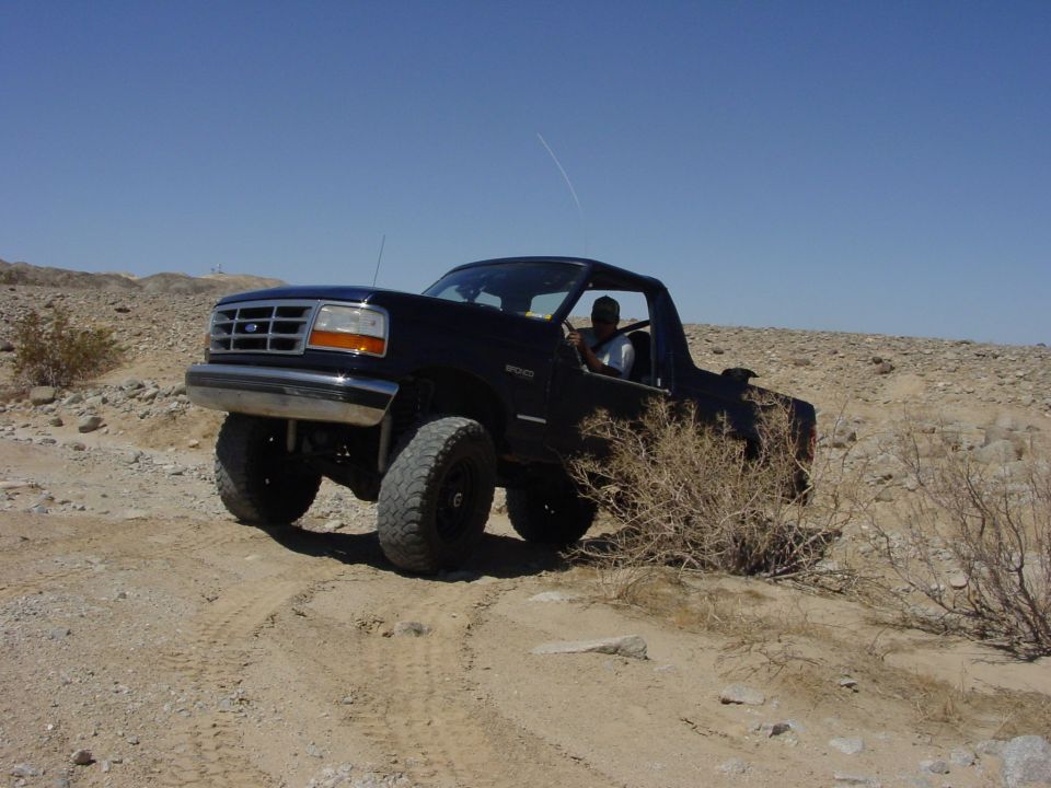 Black Ford Bronco driving on a dirt trail in a desert landscape