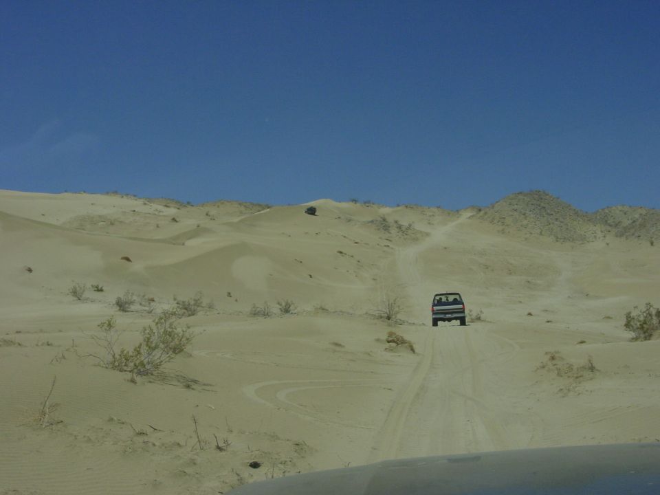 Dark SUV driving on a sandy trail in the desert