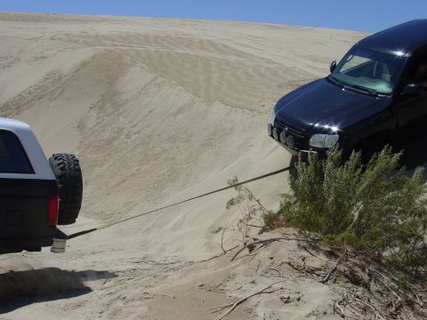 1994 Ford Bronco - Two SUVs stuck in sand dunes, one towing the other. Supermotors.net logo is present.
