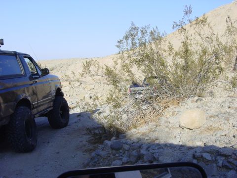 1994 Ford Bronco - A 1994 Ford Bronco navigates a rocky desert path, with another vehicle visible in the background.