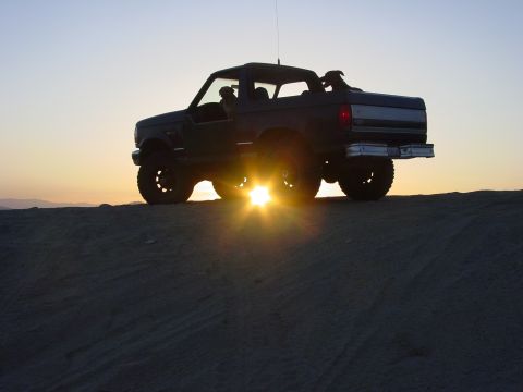 1994 Ford Bronco - Sunset silhouette of a 1994 Ford Bronco with dogs enjoying the view from a sandy dune.