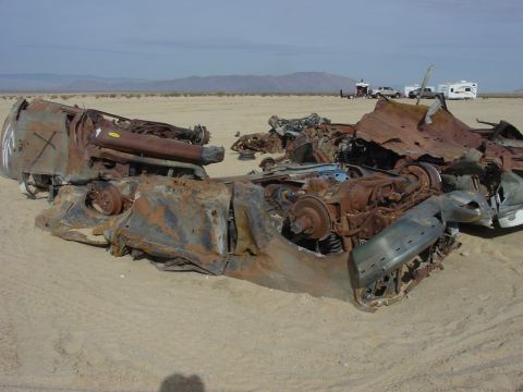 1994 Ford Bronco - This heavily damaged vehicle lies in a desert landscape with mountains in the background.