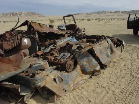 1994 Ford Bronco - Extensive vehicle damage in a desert scene, with a second vehicle visible in the distance.