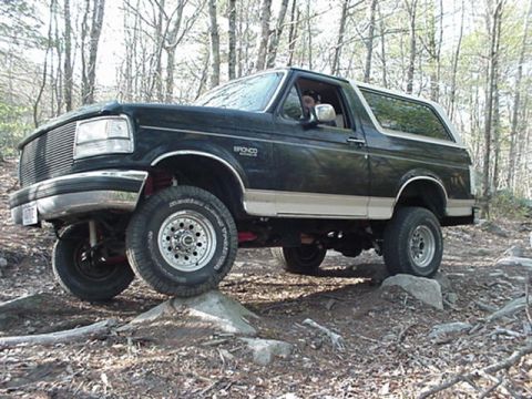 1993 Ford Bronco - This Ford Bronco is navigating a rocky trail in a forest setting.