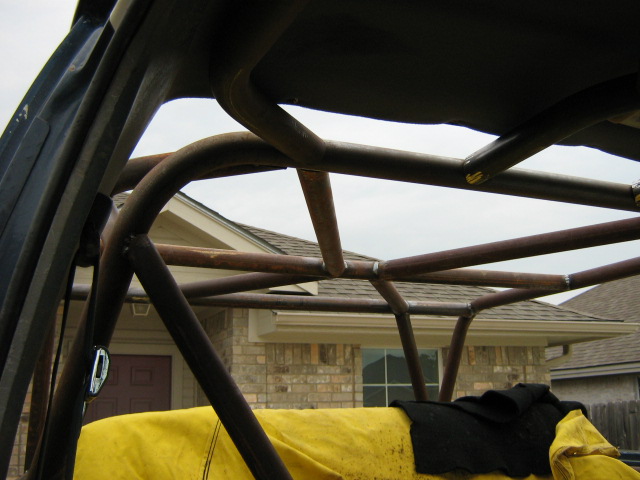 Roll cage structure inside a vehicle, with a yellow tarp visible