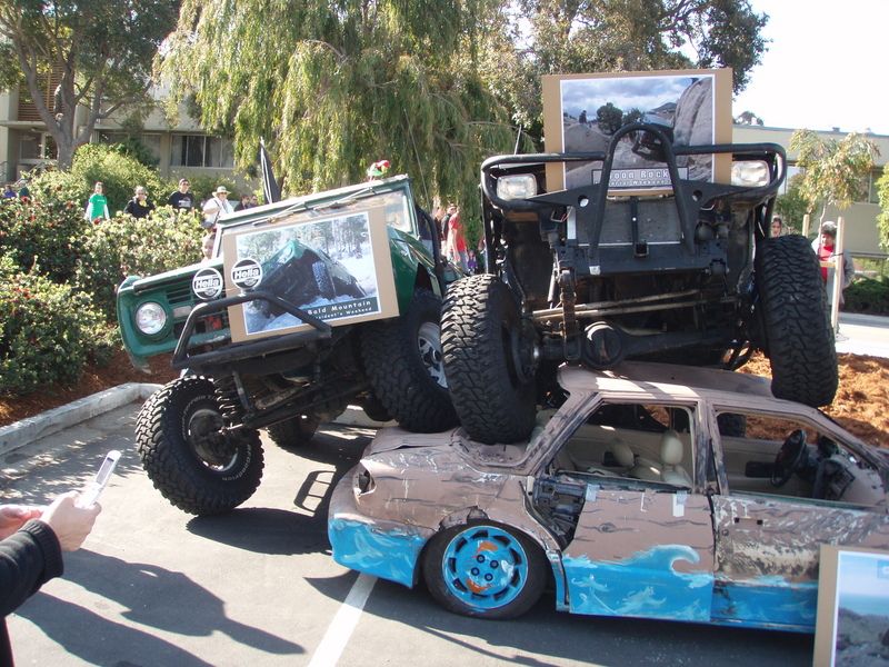 Green off-road vehicle and black off-road vehicle on top of a crushed car