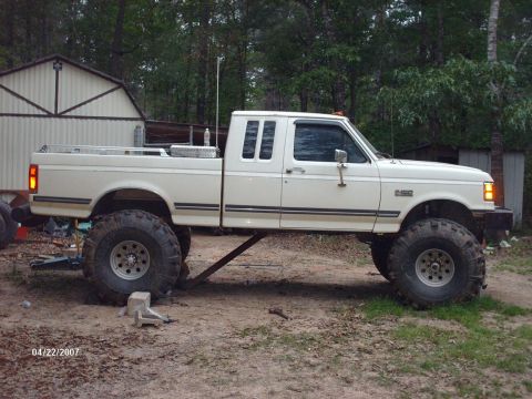 1990 Ford F-150 - Side view of a lifted 1990 Ford F-150 pickup truck with oversized tires.