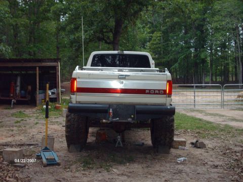 1990 Ford F-150 - Rear view of a lifted 1990 Ford F-150 with large tires, parked in a rural setting.