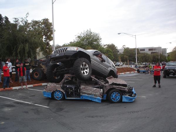Lifted Jeep atop wrecked cars in parking lot