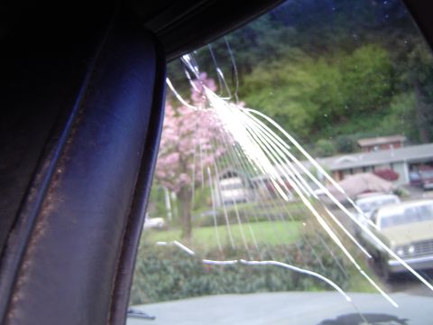 1978 Ford Bronco - View through a damaged windshield reveals a residential area with multiple vehicles and trees.